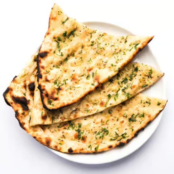 Three pieces of golden-brown naan bread, garnished with green herbs, on a white plate.